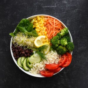 A home-cooked plate with roasted vegetables, whole grains, beans, and fish on a kitchen table.