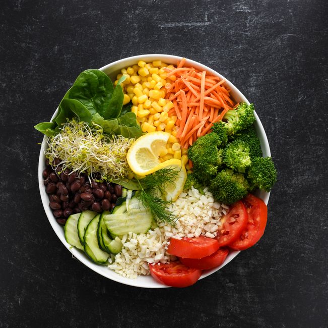 A home-cooked plate with roasted vegetables, whole grains, beans, and fish on a kitchen table.